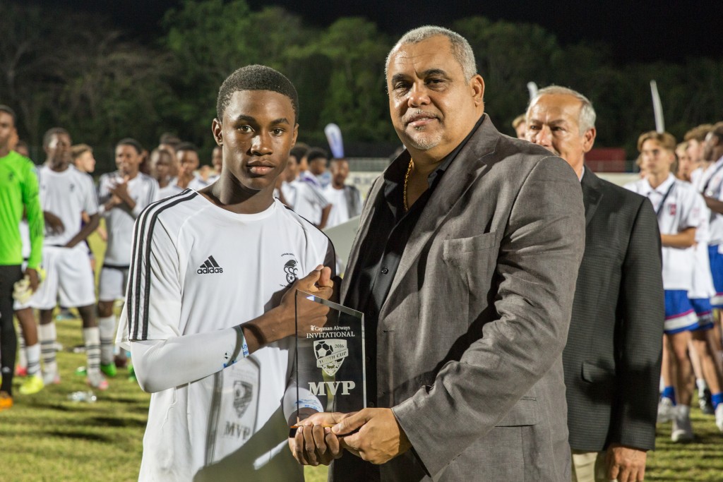 Hon. Osbourne Bodden, Minister of Community Affairs, Youth and Sports, presents the MVP award to Shanthamoi Brown of Cavalier FC.